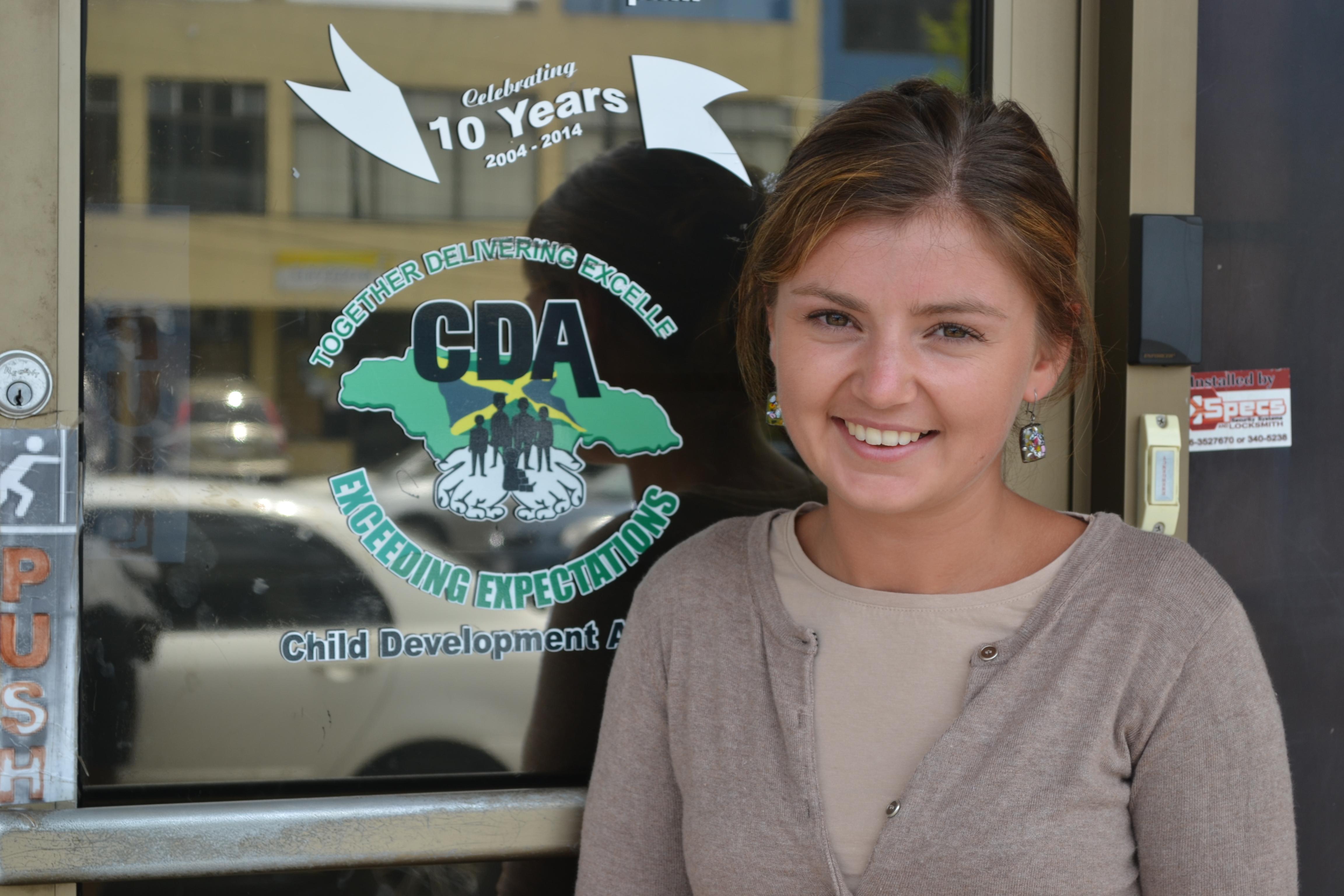Projects Abroad Psychology intern stands outside the Child Development Agency in Jamaica. Female Childcare and Psychology worker is standing outside the Child Development Agency in Jamaica during an internship placement.